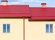 Rich red roof colour against a yellow house.