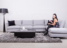 Woman sitting on grey couch in an open plan living space