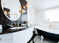Bathroom with black tiled feature wall and round mirror