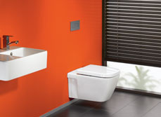 Bathroom with orange wall and wall mounted toilet and vanity
