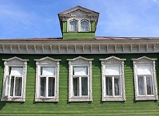 Green house with white framed and pointed windows with mouldings