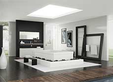 Black and white motif bathroom with raised white bath surrounded by black rocks.