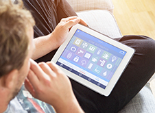 Young man using a wireless tablet to check his home security systems.