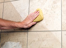 Person cleaning tiles and grout in bathroom