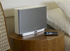 White Sonos wireless speaker and iphone with Sonos Play 5 app.