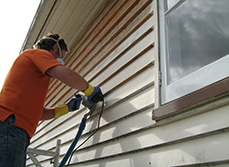 Worker stripping paint off weatherboards using the paint shaver pro.