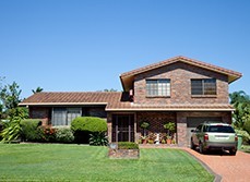 A brick house with a car park next to it