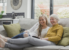 A mother and daughter relaxing on a sofa in a home.