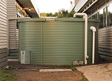 Rainwater tank installed between and connected to two houses