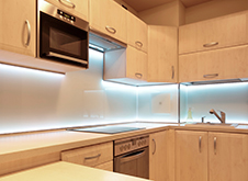 Kitchen cupboards with light blue tinted light bulbs underneath.\n