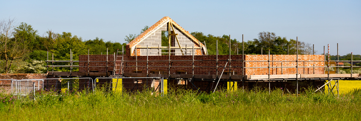 A home under construction with blue skies and yellow flowers