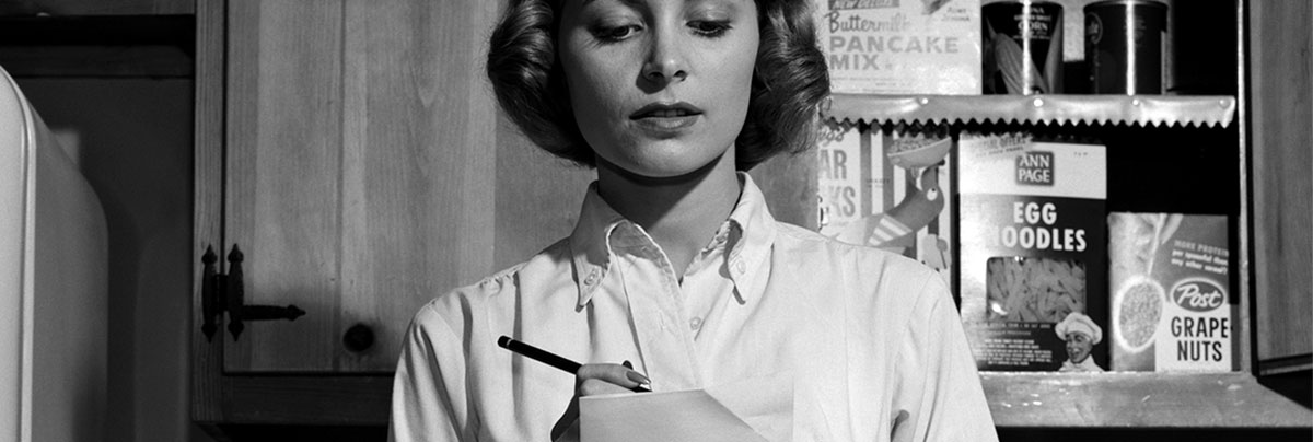 Black and white 1950s photo of women writing shopping list for pantry needs