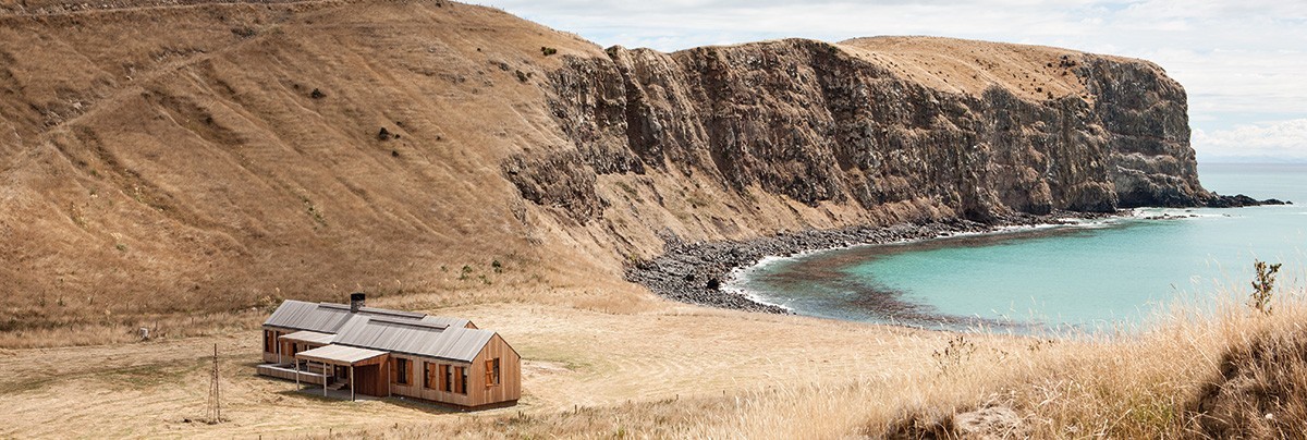 The modern farmhouse sits alone next to the bay