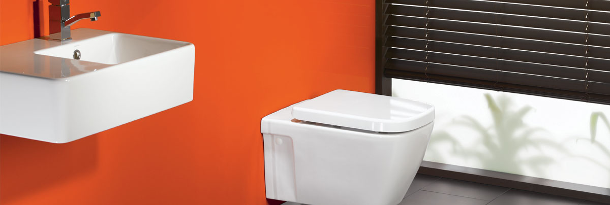 Bathroom with orange wall and wall mounted toilet and vanity