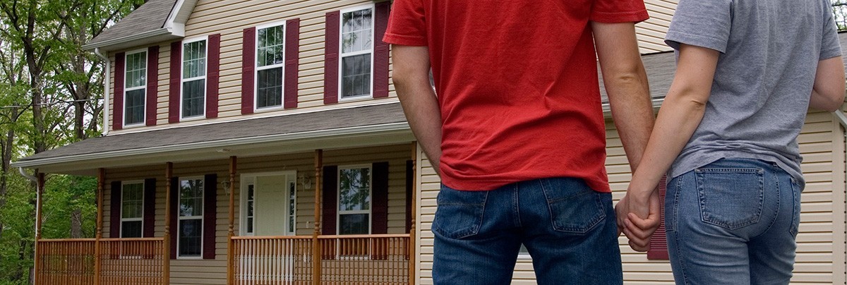 Couple holding hands outside their first home.