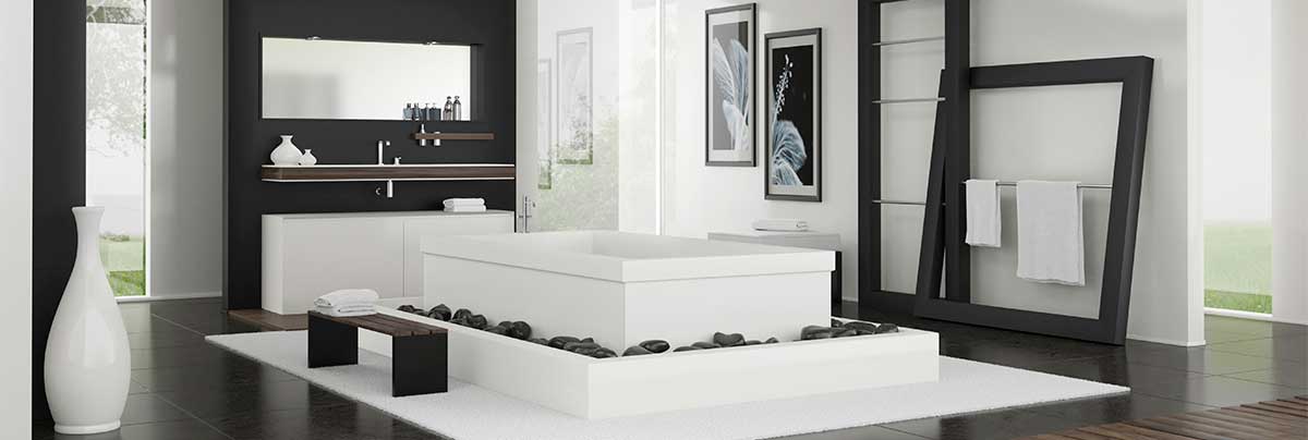 Black and white motif bathroom with raised white bath surrounded by black rocks.