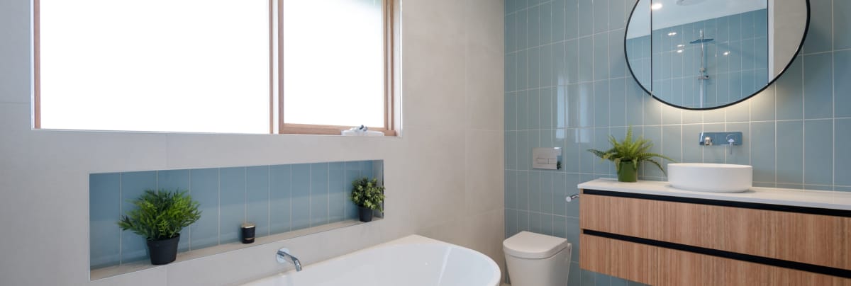 bathroom with light blue tiles and round mirror