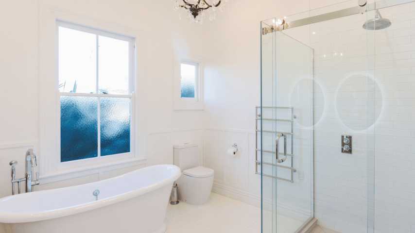 A Completed white bathroom renovation with double LED surrounded mirrors that you can see in the reflection.