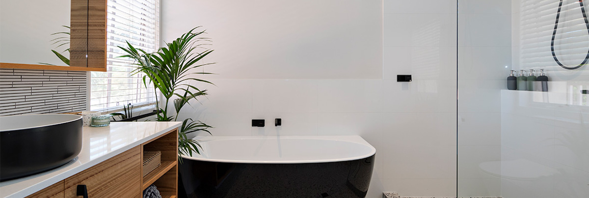 Black freestanding tub with tropical plant in the renovated bathroom