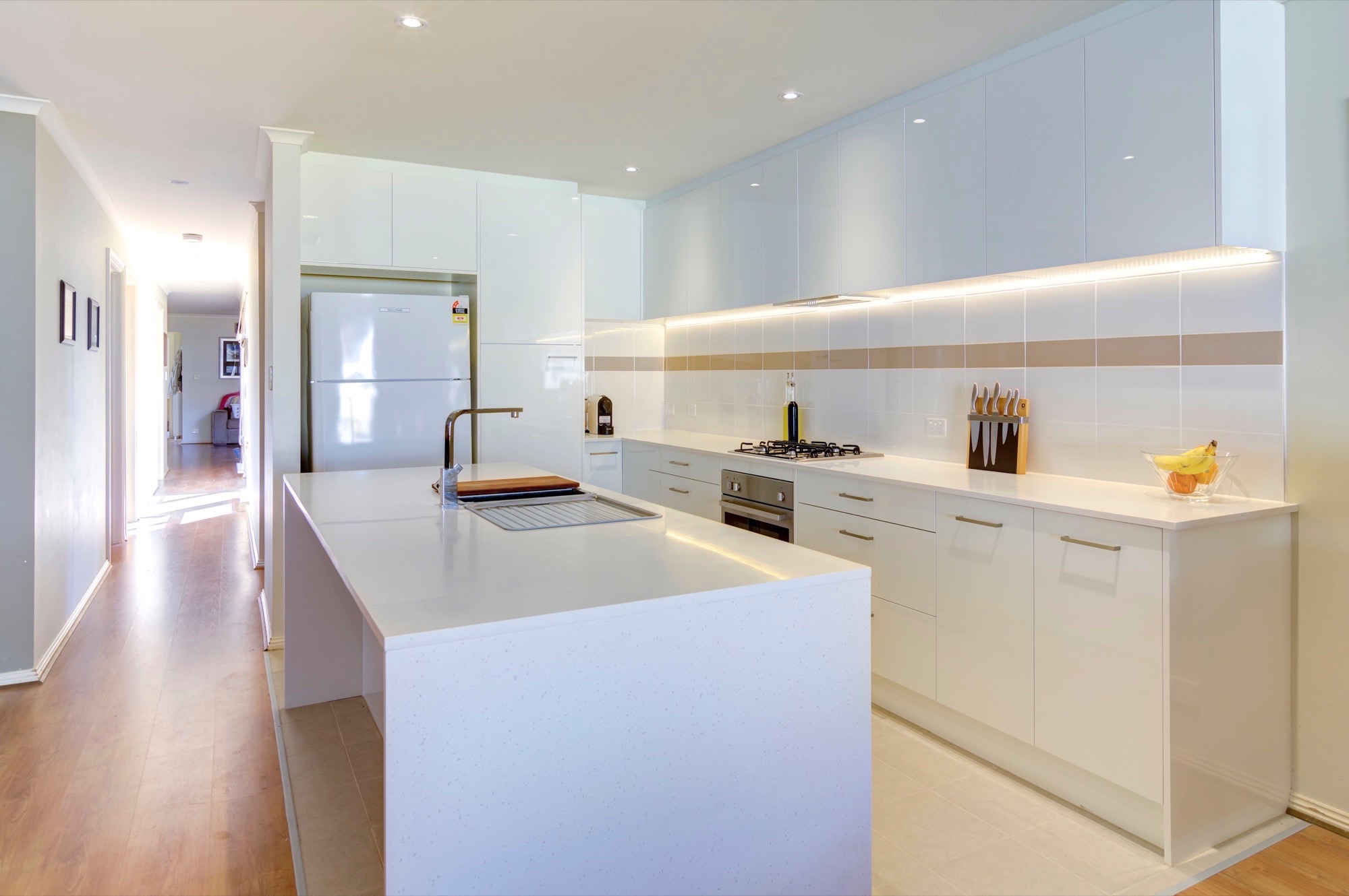 Chic white kitchen with lighting in the backsplash