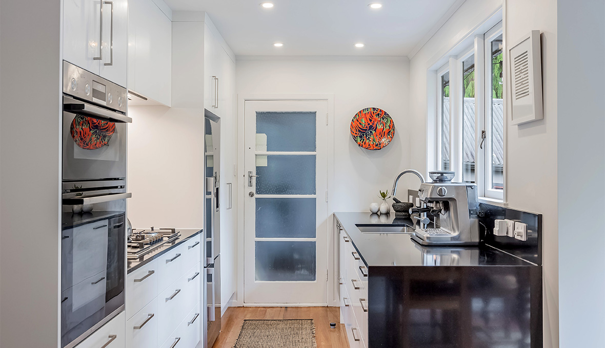 Small white kitchen renovation in west Auckland with a black sink top
