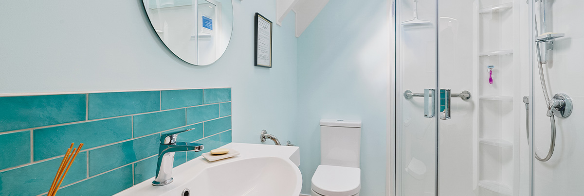 small bathroom with sloped ceilings and turquoise tiles