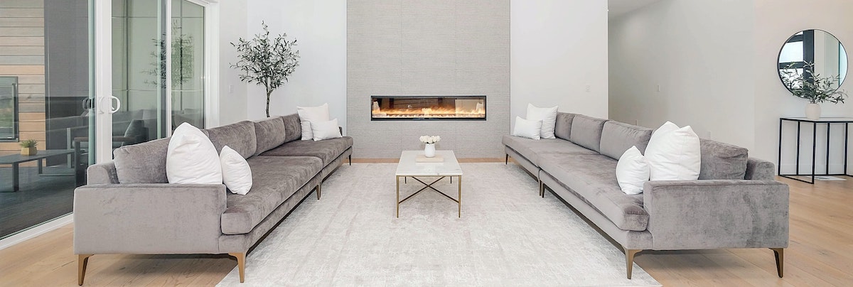 two grey couches facing each other in front of a fireplace