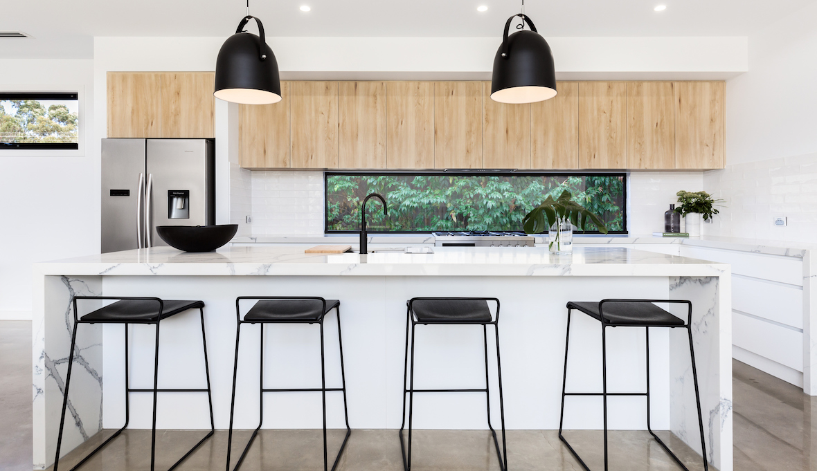 bar stools in front marble kitchen island in a modern kitchen with wooden cabinets