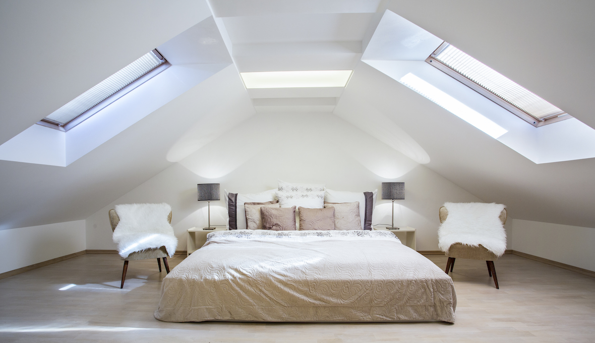 bed on a loft with to big windows on each side of the sloped ceilings