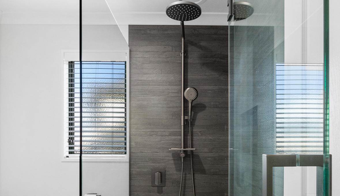 glass shower with dark grey tiles