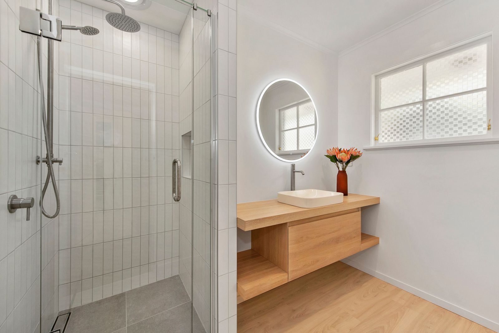 wooden sink underneath round mirror with LED lights