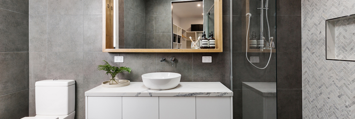 bathroom with grey tiles, glass shower and marble sink top