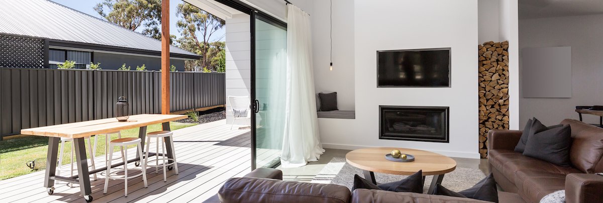 indoor outdoor flow lounge with tv above fireplace