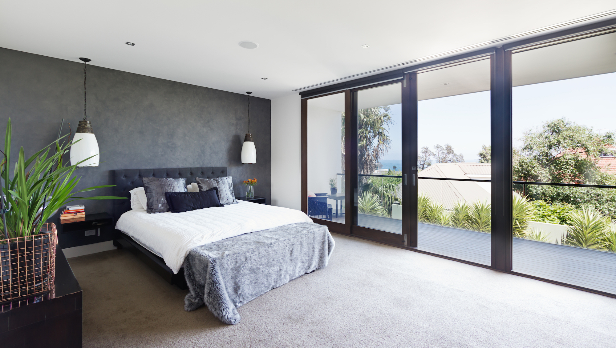 bedroom with a feature wall and sliding doors for indoor outdoor flow
