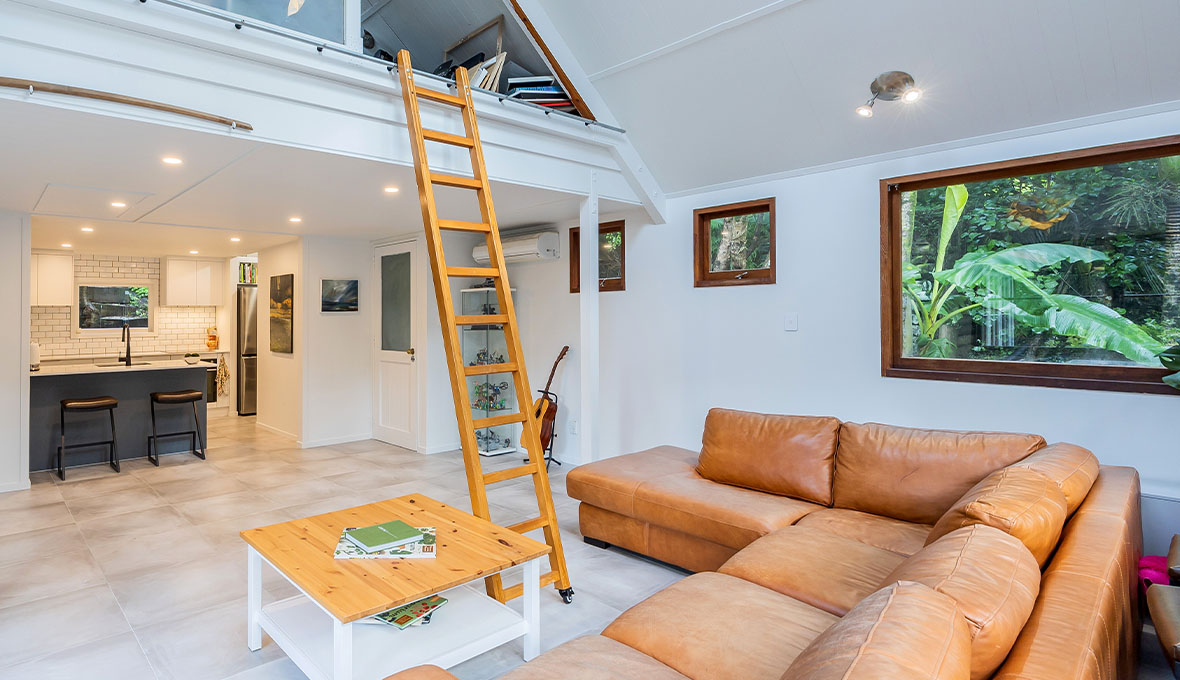 A cosy living room with a wood ladder giving access to the loft storage space in the living room