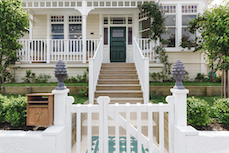 Front of villa exterior with wooden steps and white railing leading to a green front door