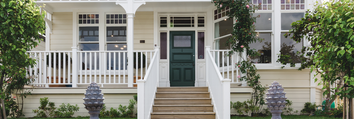Front of villa exterior with wooden steps and white railing leading to a green front door