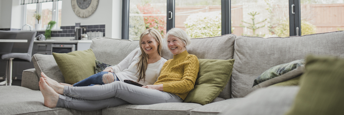 A mother and daughter relaxing on a sofa in a home.