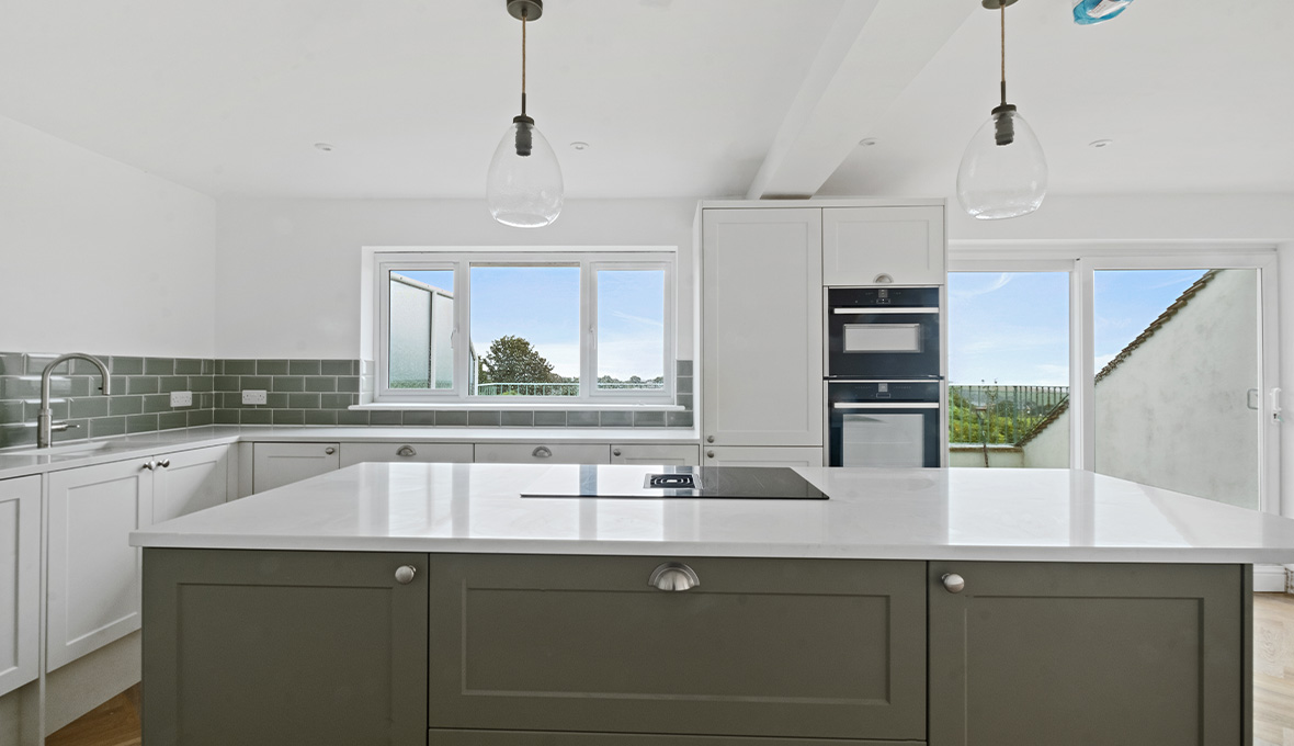 Simple white kitchen renovation in Brighton UK featuring kitchen island and pendant lights