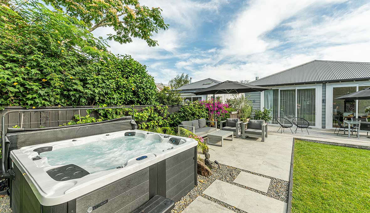 Spa pool with paved outdoor seating with outdoor umbrellas.