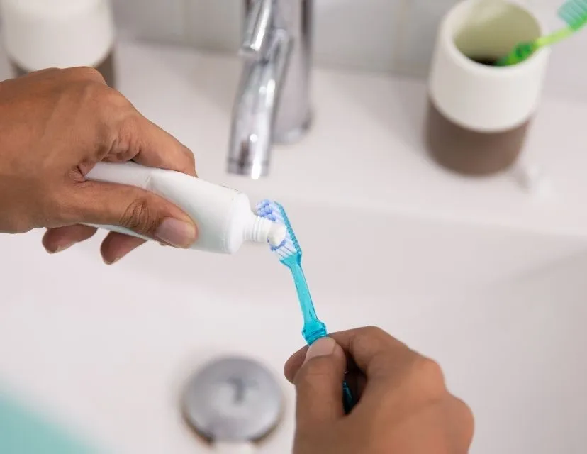 Person putting toothpaste onto a toothbrush