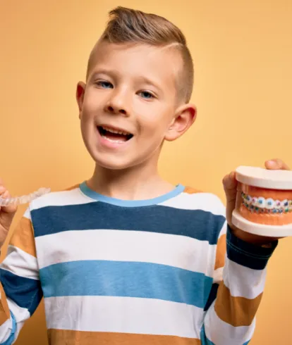 Child holding retainer and braces prop