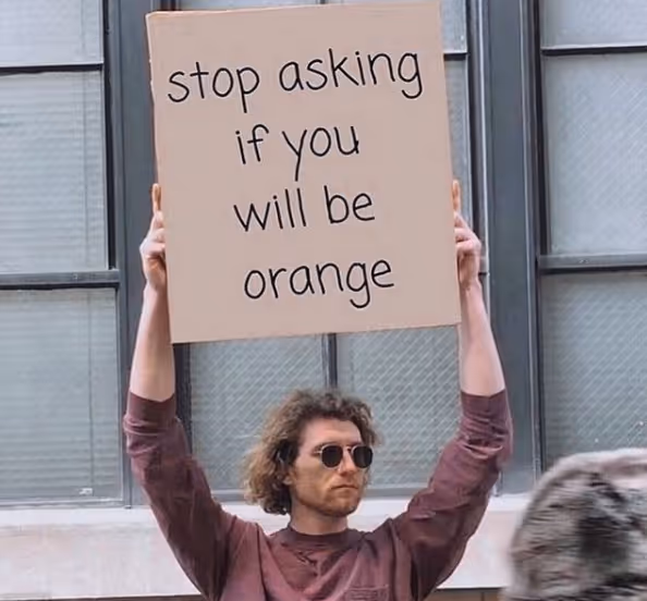a guy holding a sign that says stop asking if you will be orange