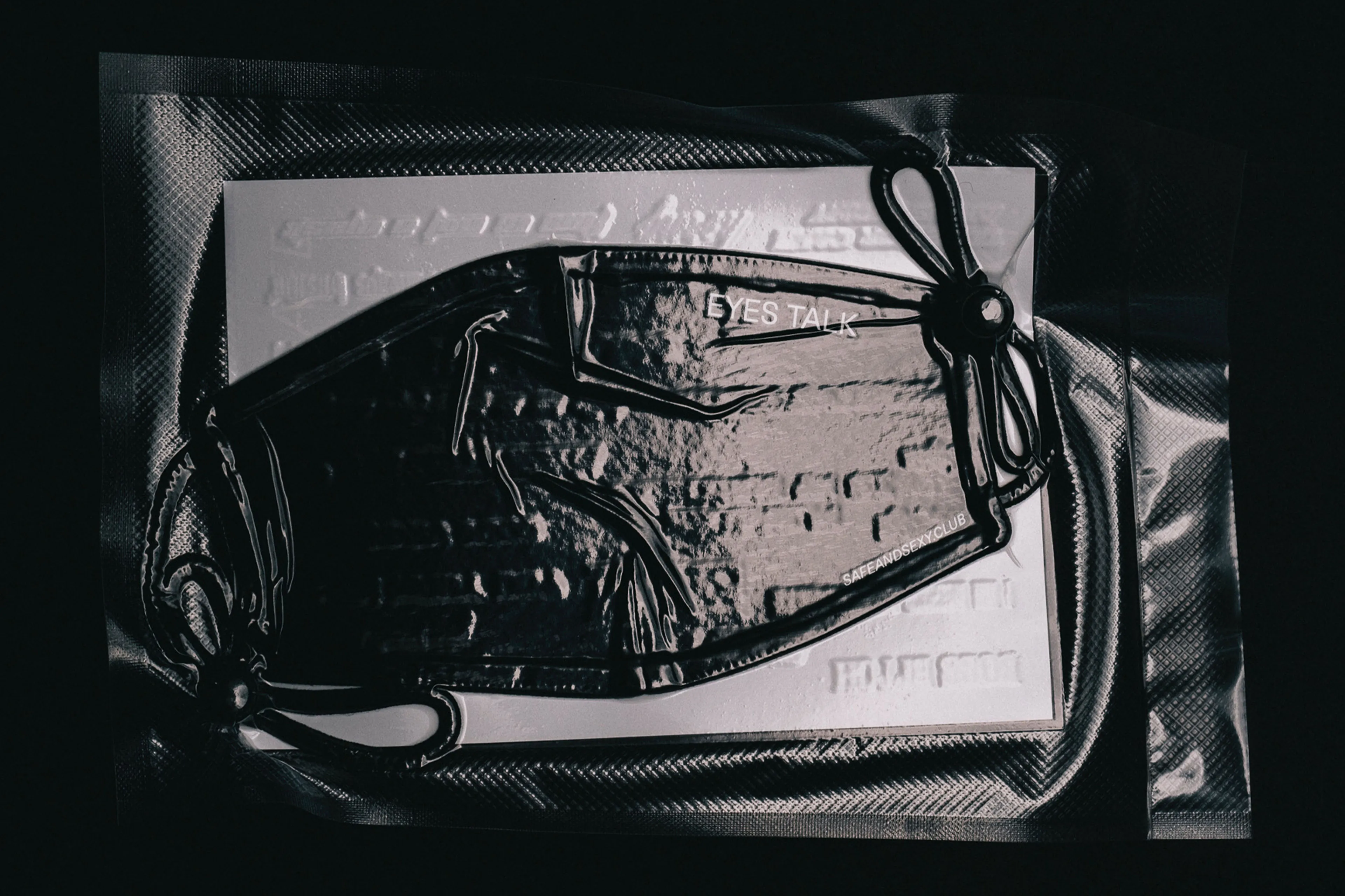 Foto einer eingeschweißten Stoff-Gesichtsmaske (Mund-Nasen-Schutz) mit Aufschrift "EYES TALK".