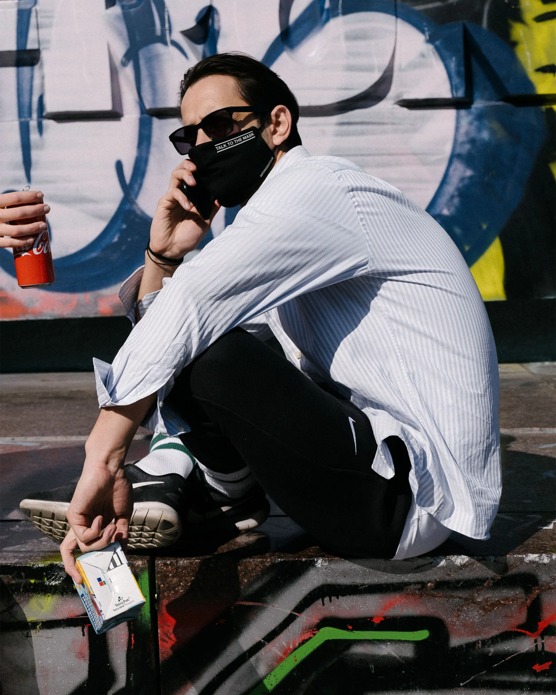 Foto einer Person mit Stoff-Gesichtsmaske mit aufschrift "TALK TO THE MASK".