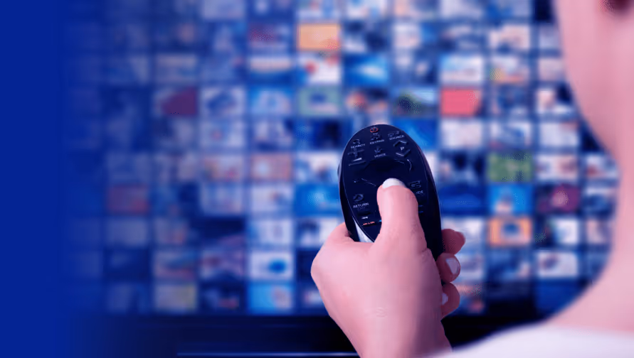 User holding a remote in front of a TV with streaming service icons, highlighting SaaS security challenges.