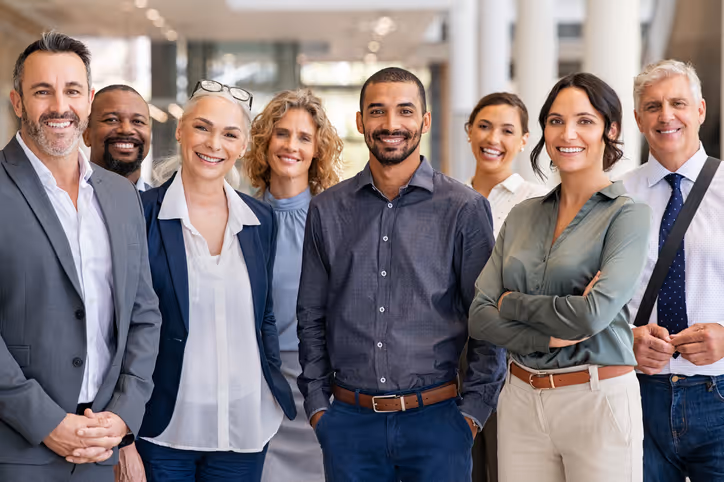 Diverse business team smiling and standing together in an office hallway.