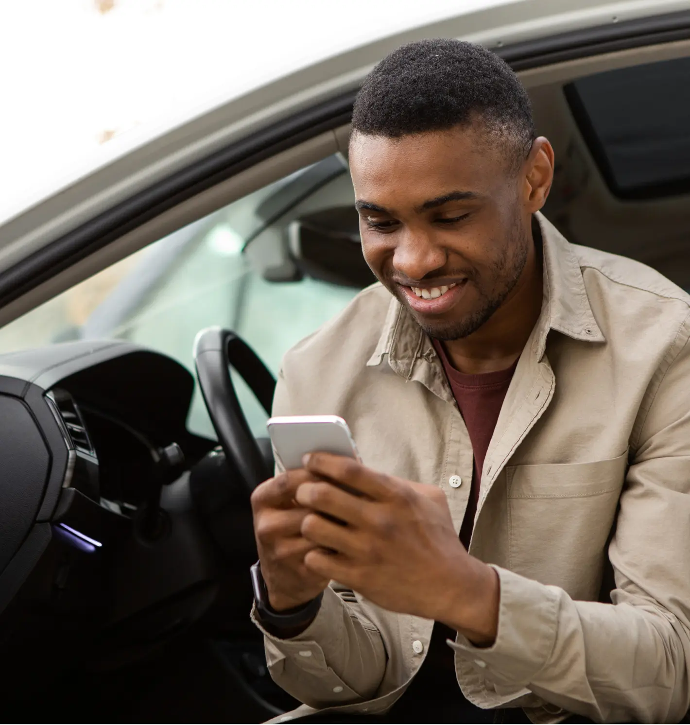 Delightful man smiling while looking at his phone.