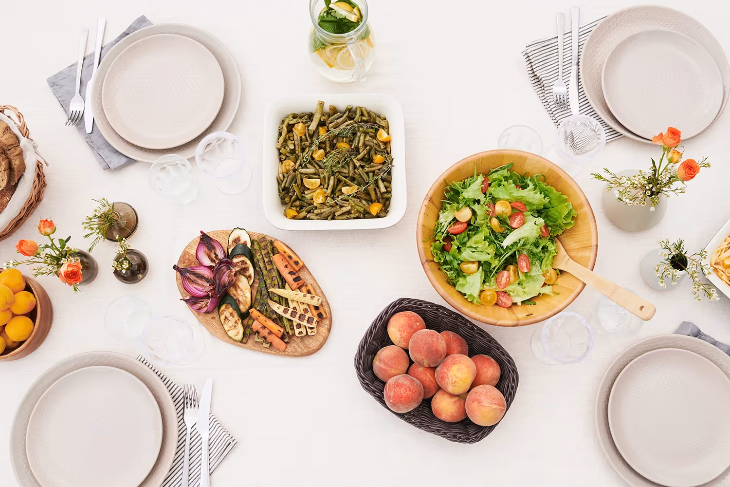 bowls and plates filled with salad, roasted vegetables and various types of fruit on a table