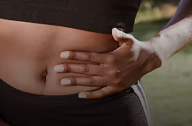Close-up of a person’s hand resting on their bare abdomen, wearing a black sports outfit.